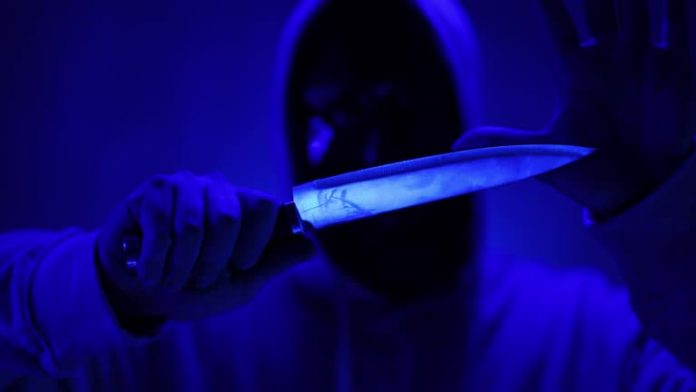 Scary man in a black mask holding a knife.